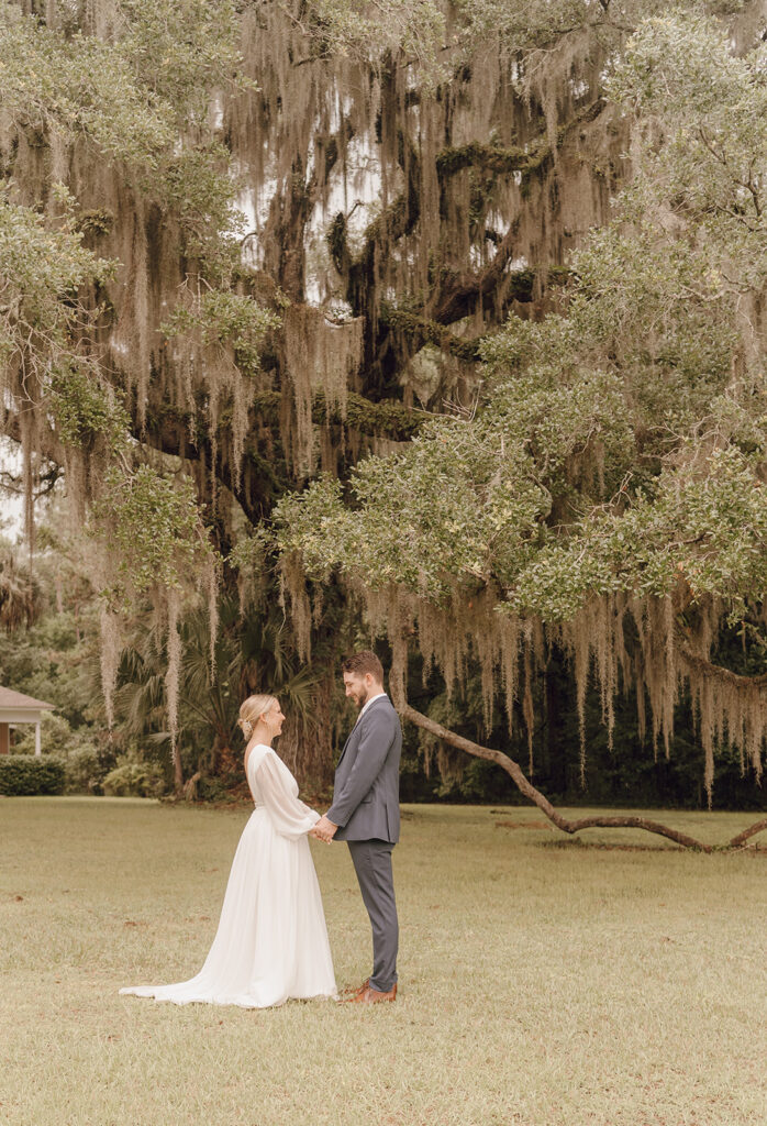 bride and groom holding hands under willow tree in maclay gardens fl state park