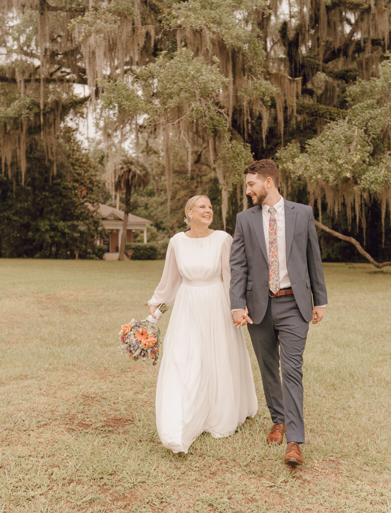 bride and groom smiling and walking in maclay gardens fl state park