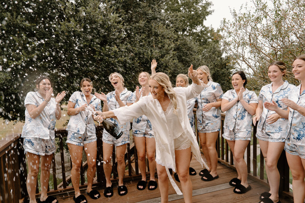 bride popping champagne with bridesmaids in pajamas