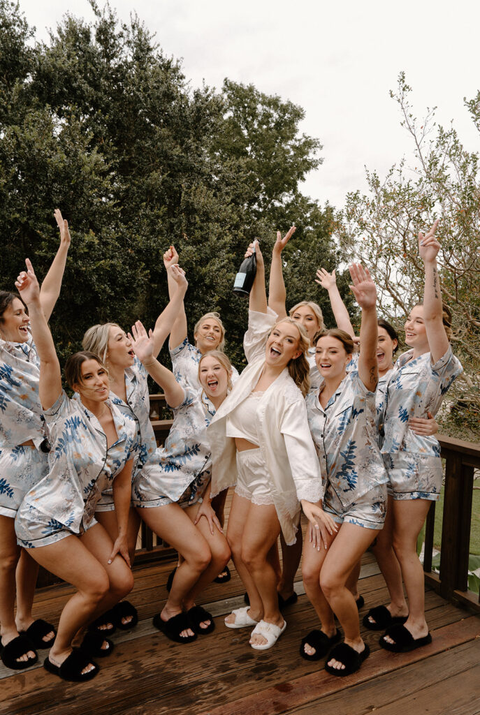 bride popping champagne with bridesmaids in pajamas 