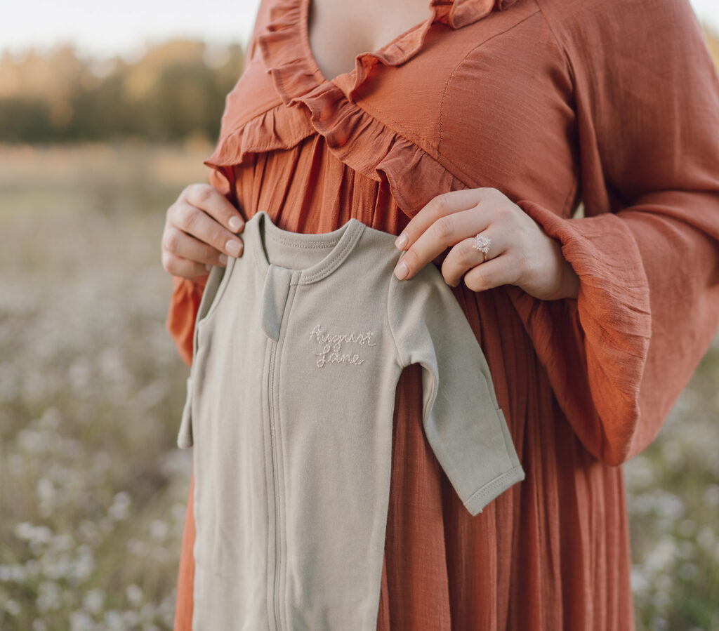 baby onesie maternity photos in a field