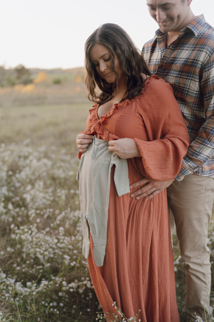field maternity photos with baby onesie