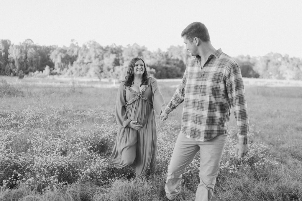 couple holding hands and walking in a field black and white photos