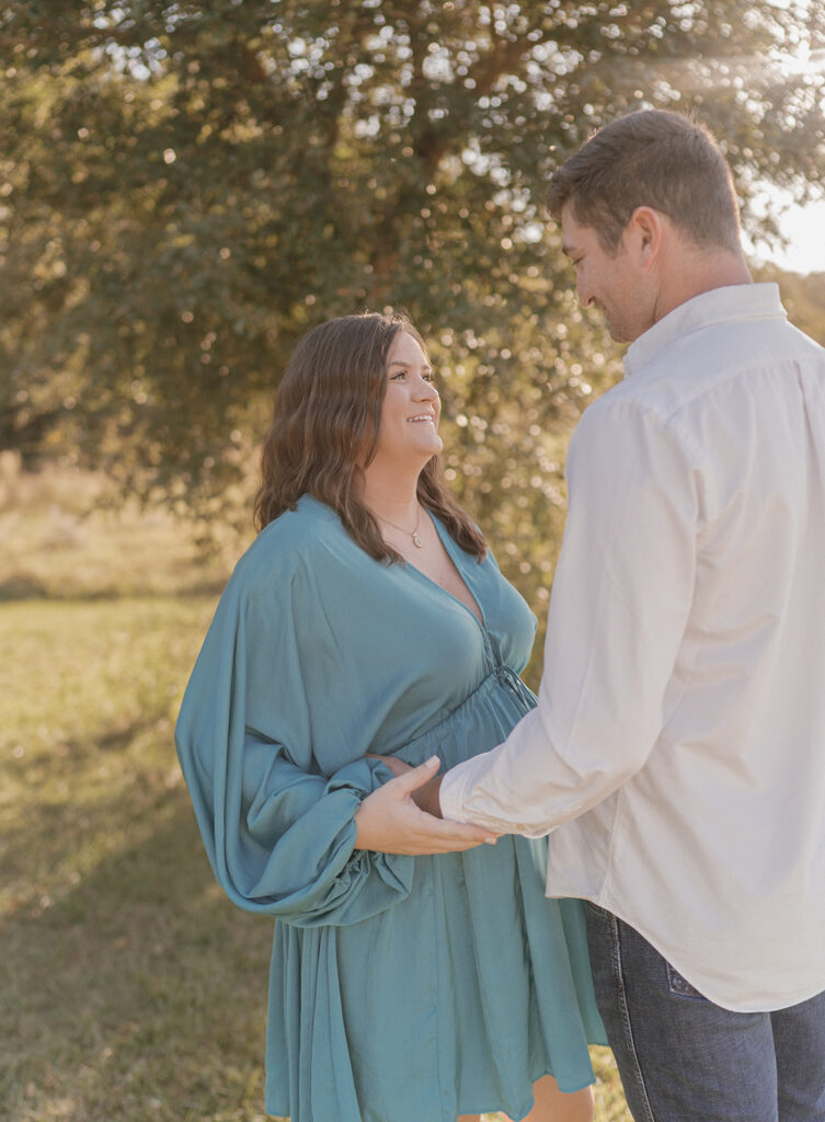 couple smiling and holding hands during maternity session