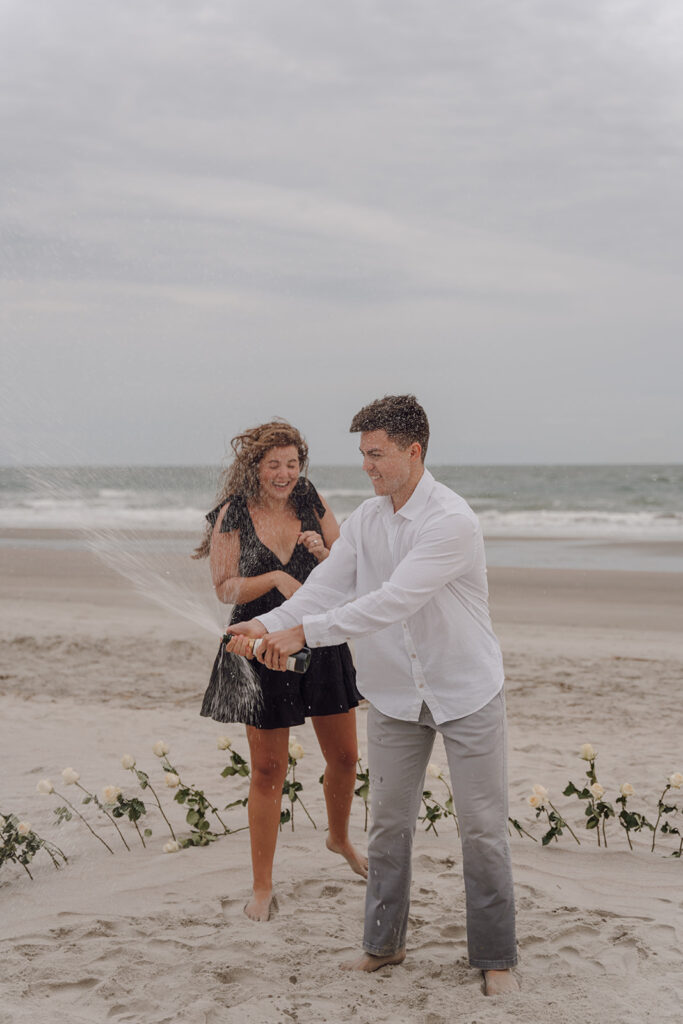 couple popping champagne during engagement