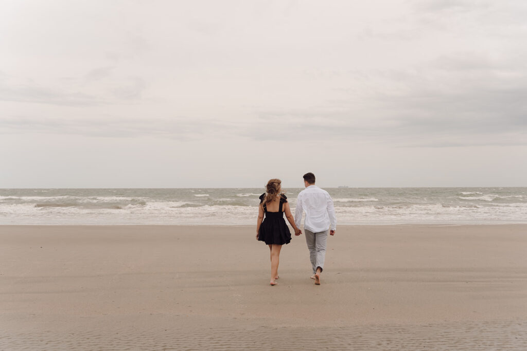 couple holding hands and walking on the beach isle of palms