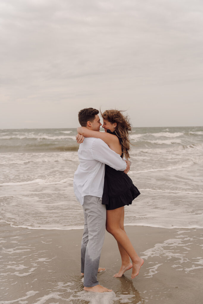 couple smiling and hugging on the shore of isle of palms