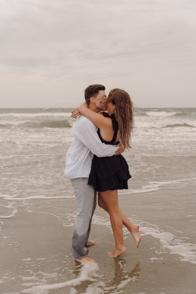 couple kissing on the beach during engagement session