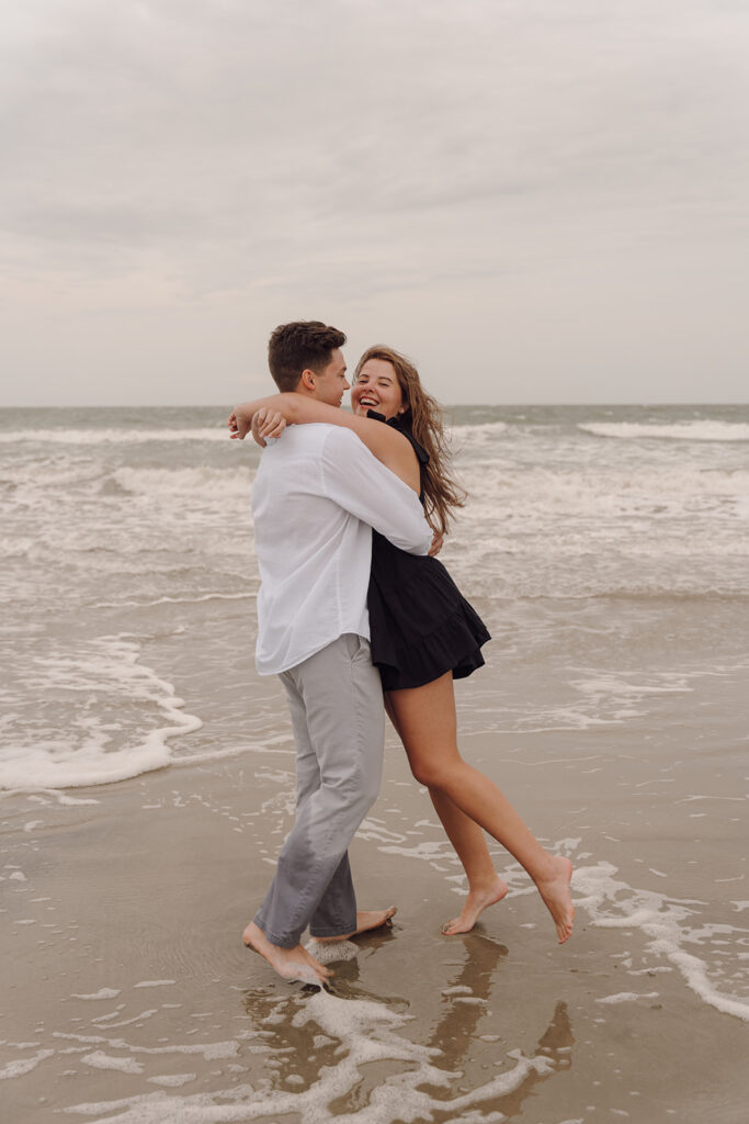 playful and candid couple poses for engagement session on the beach