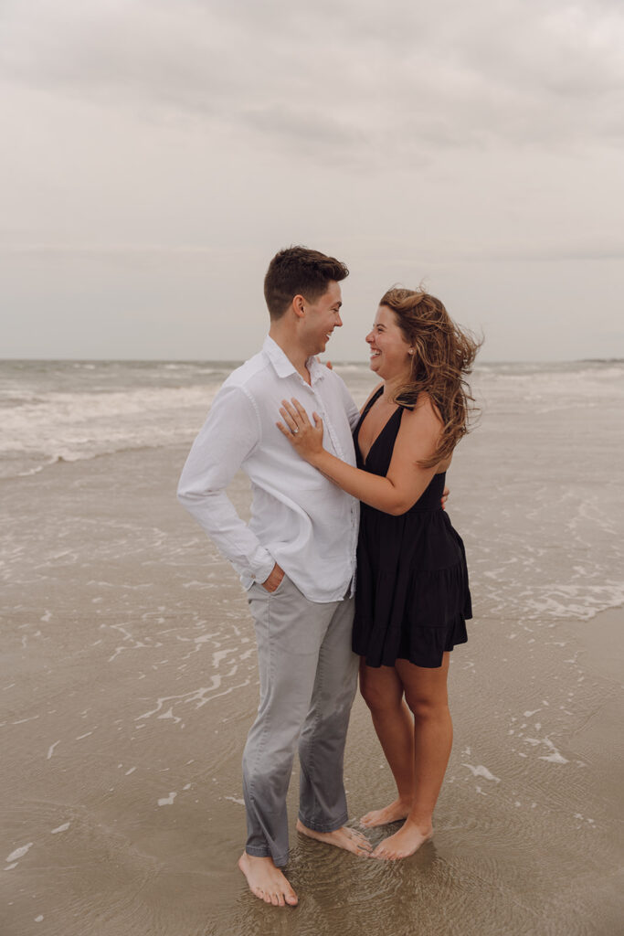 playful and candid couple poses for engagement session on the beach