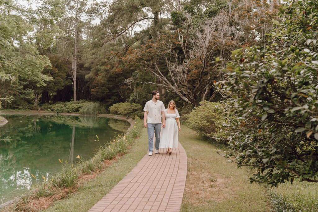 couple holding hands and walking on pathway in the park