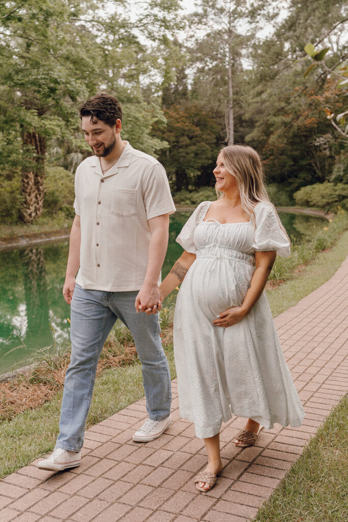 couple holding hands and walking on pathway in park