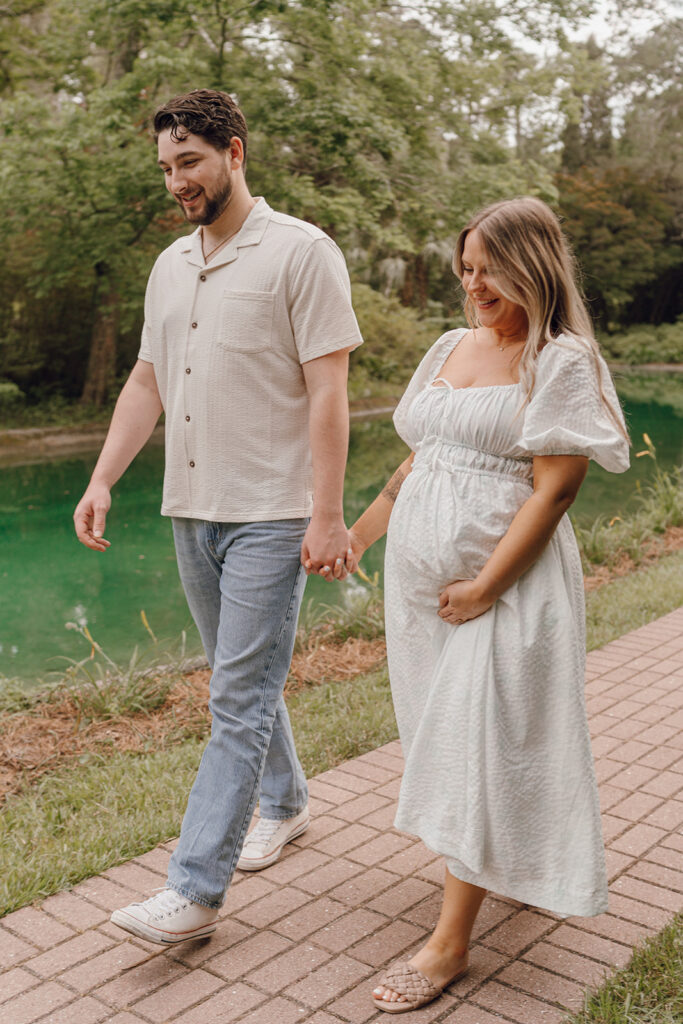 couple holding hands and walking on pathway in park