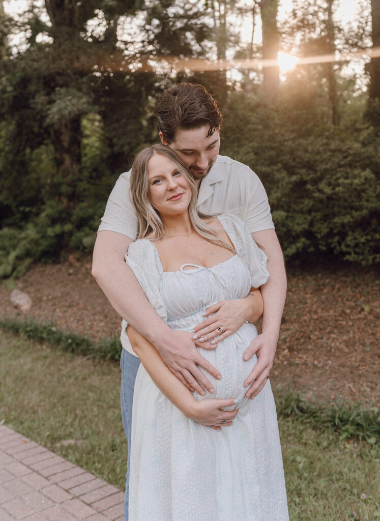 couple smiling and huggung maternity session in maclay gardens state park