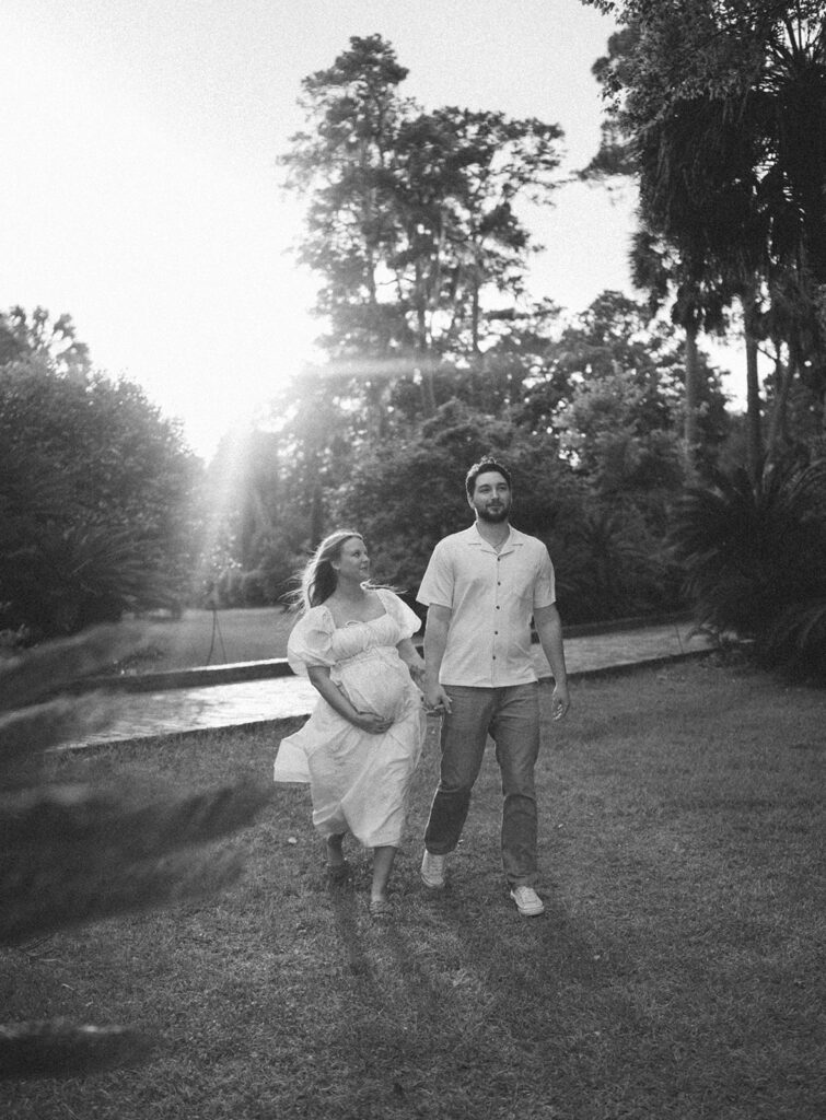 couple smiling and walking holding baby bump