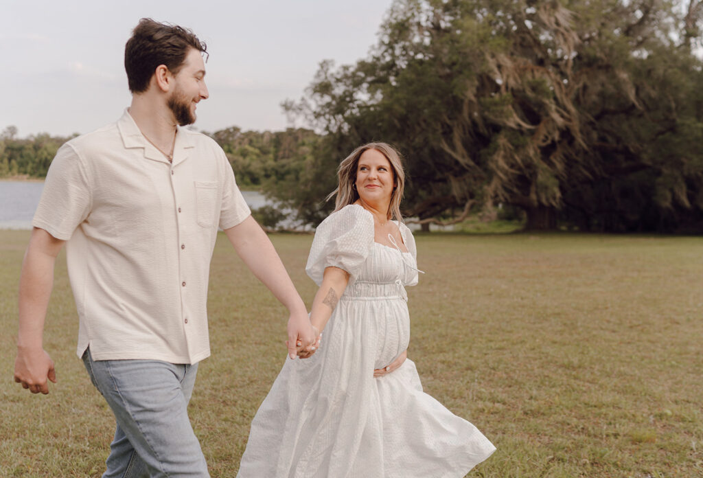 couple holding hands and running maternity session poses posing prompts