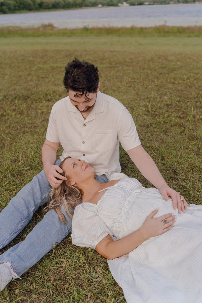 couple laying down in grass during maternity session