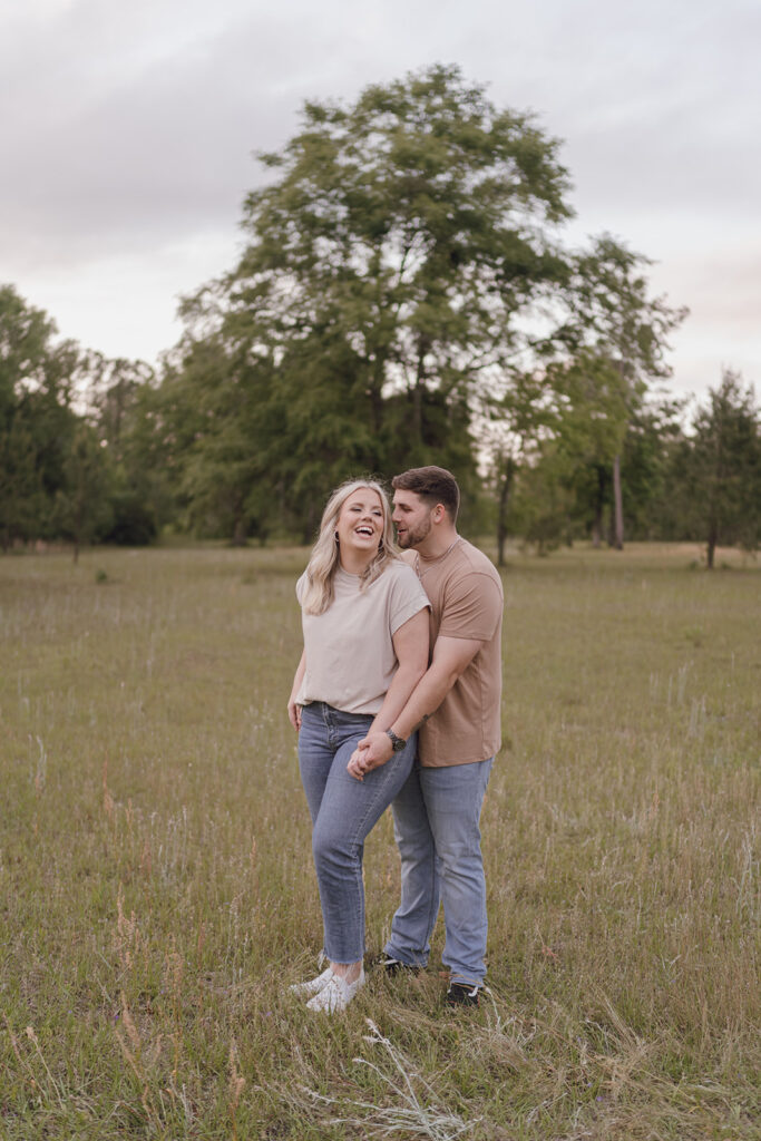 couple smiling and laughing in open grass field