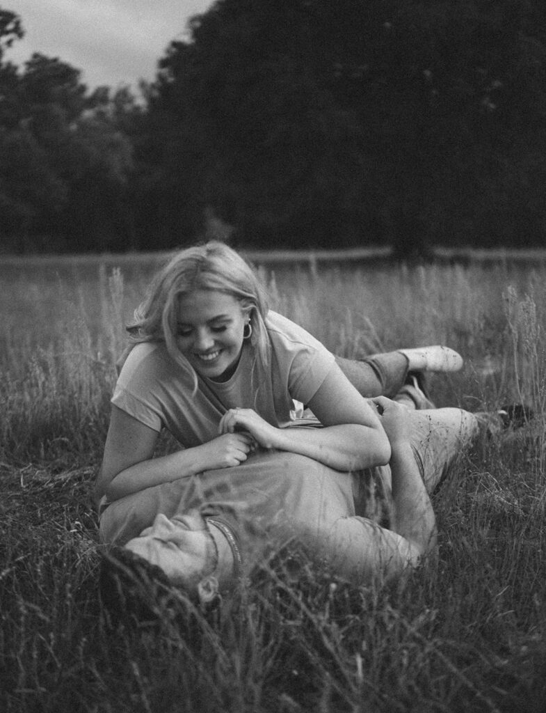 couple smiling and laughing laying down in a grass field in florida