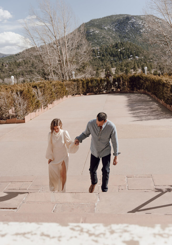 bride and groom walking up the stairs to the stanley hotel and holding hands