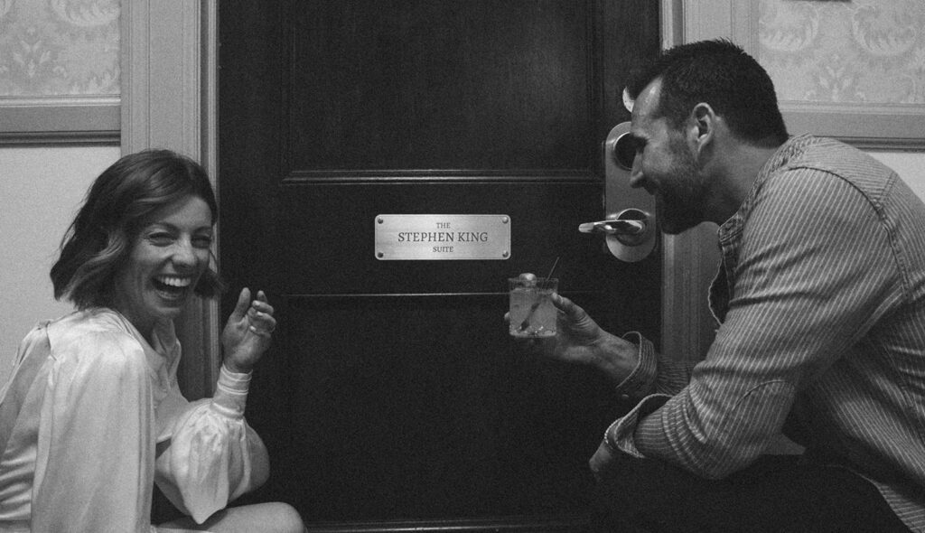 bride and groom posing in front of the stephen king suite in the stanley hotel