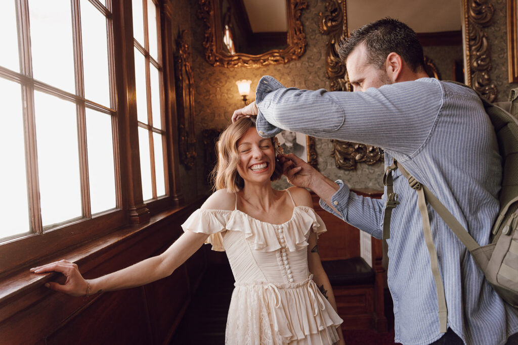 groom helping bride get ready for wedding ceremony