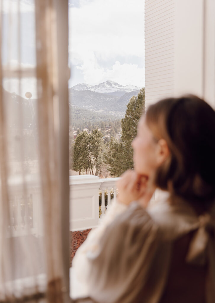 bride looking out window at the mountains getting ready wedding photos