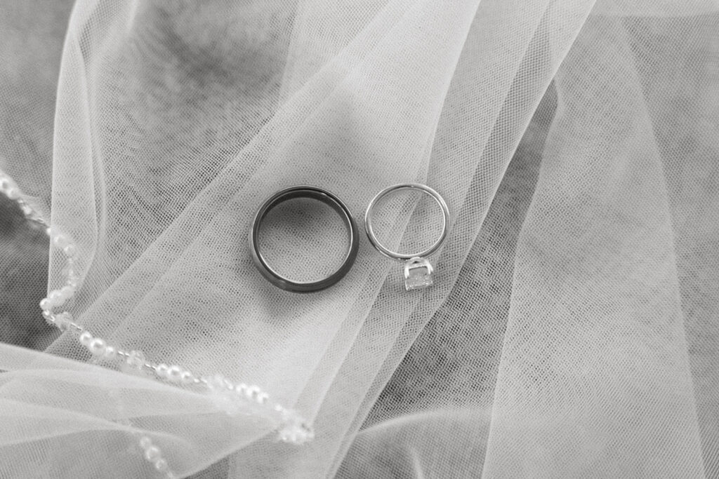 wedding details flatlay rings and veil