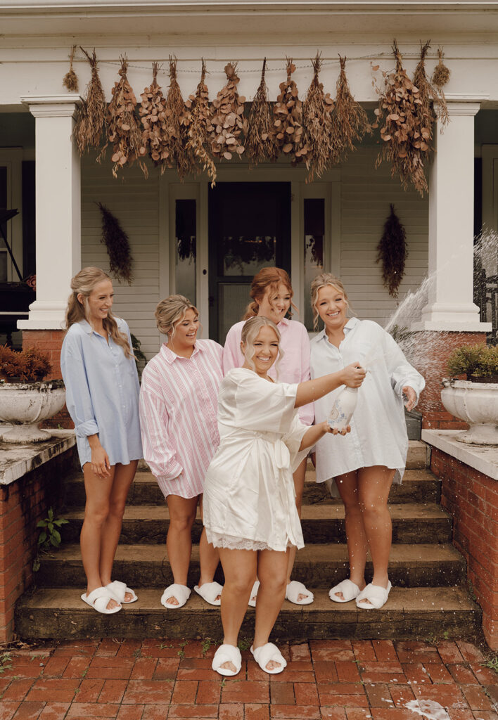 bride popping champagne with bridesmaids wedding getting ready photos