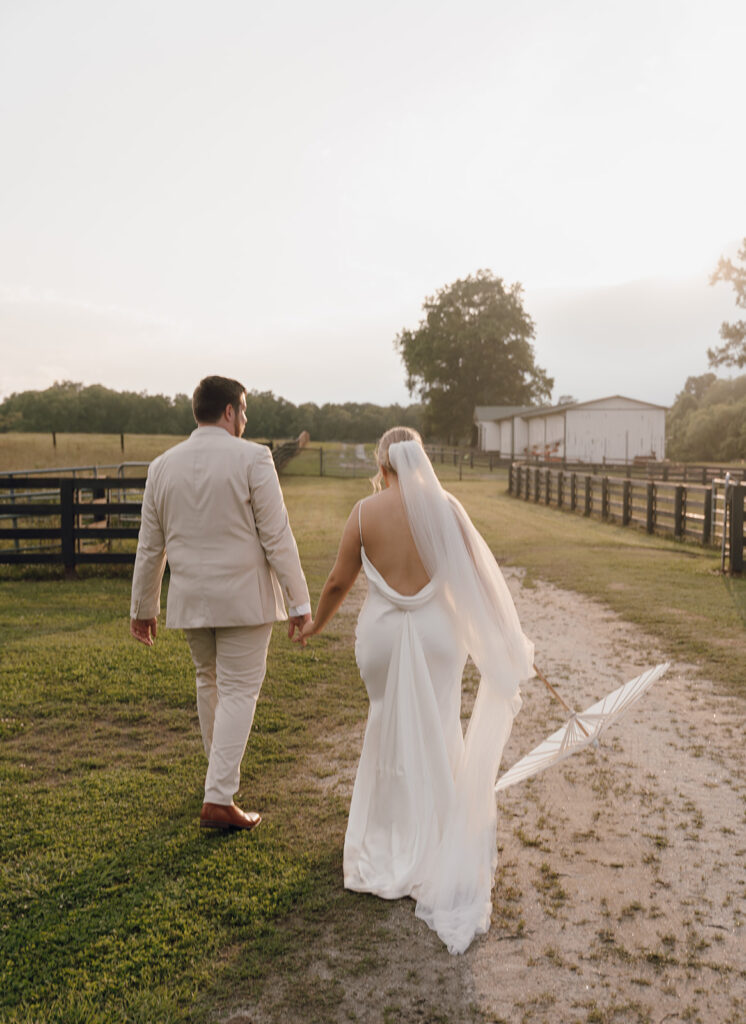 bride and groom holding hands and walking on farm venue