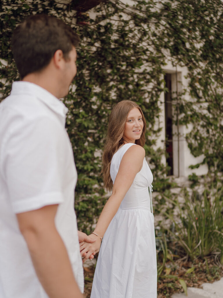 couple holding hands and walking on sidewalk