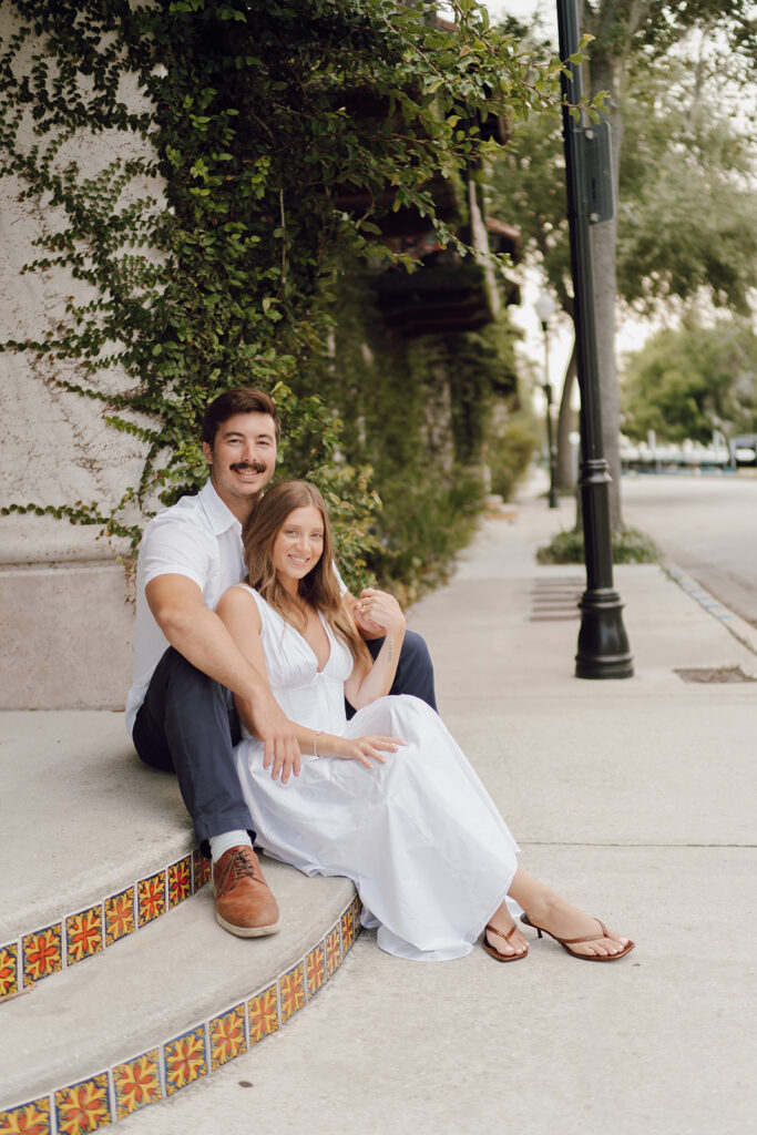 couple smiling and posing on steps for engagement