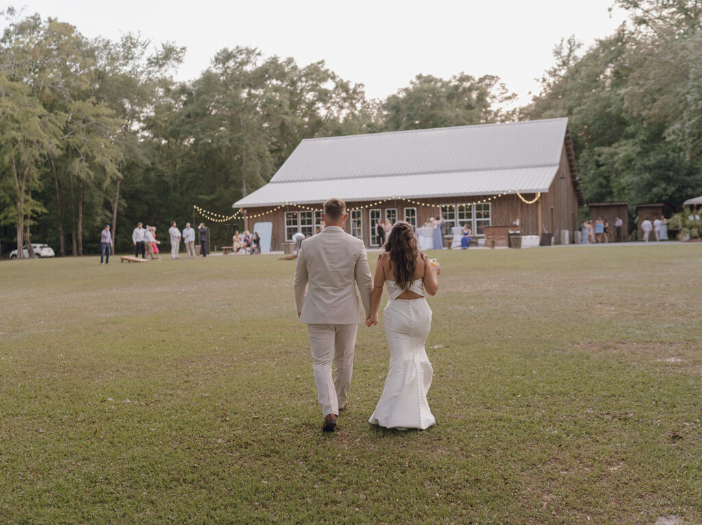 bride and groom walking up to reception barn