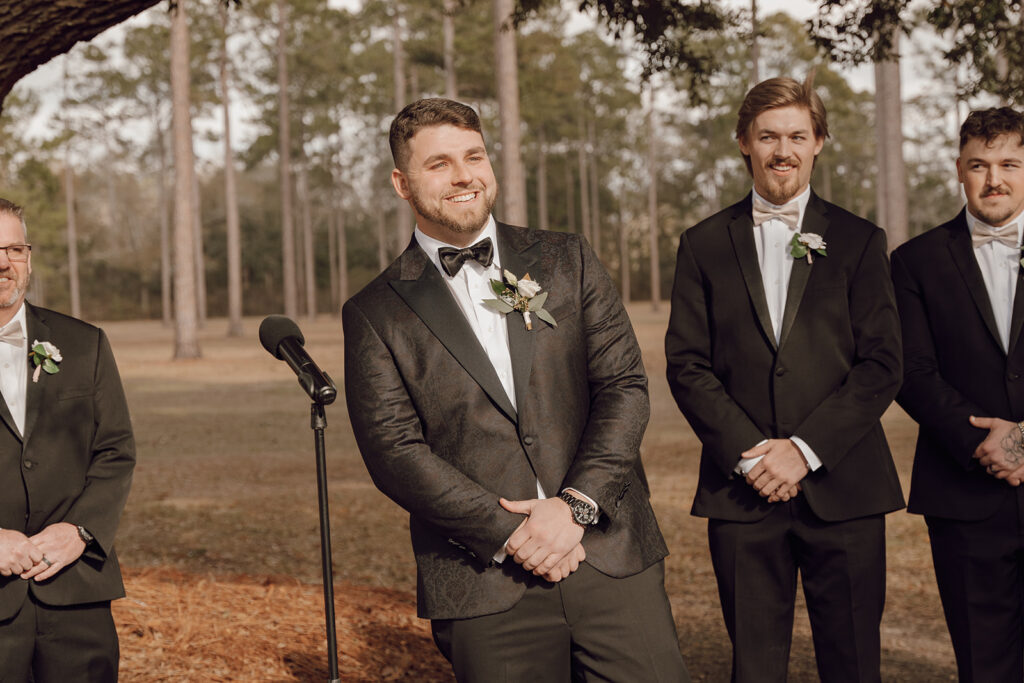 groom smiling at bride walking down the aisle