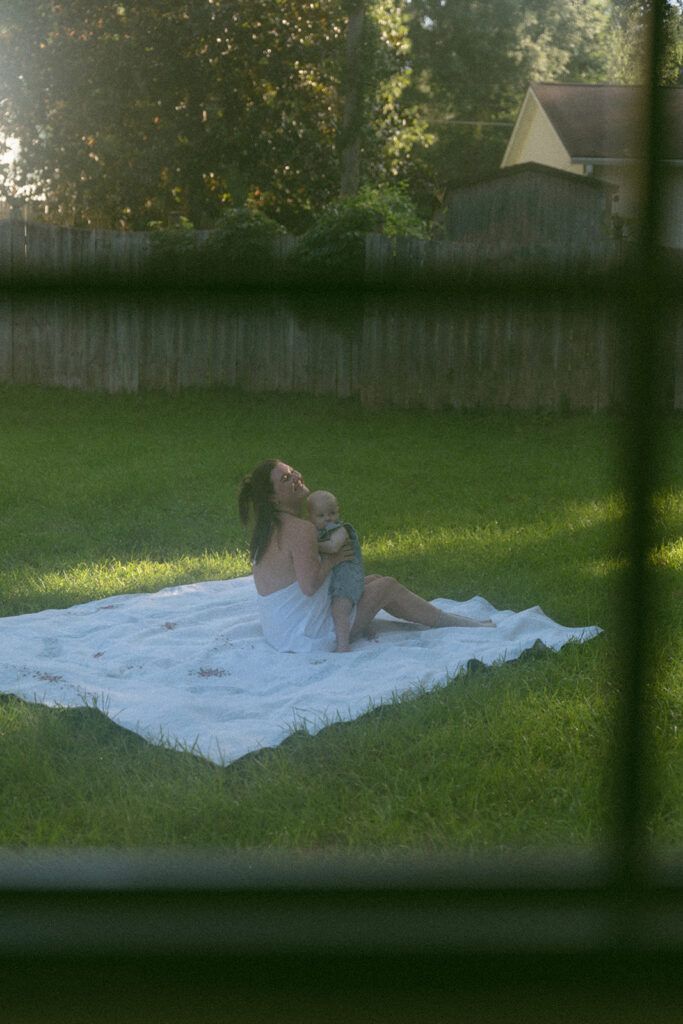 mom and baby playing on picnic blanket in backyard