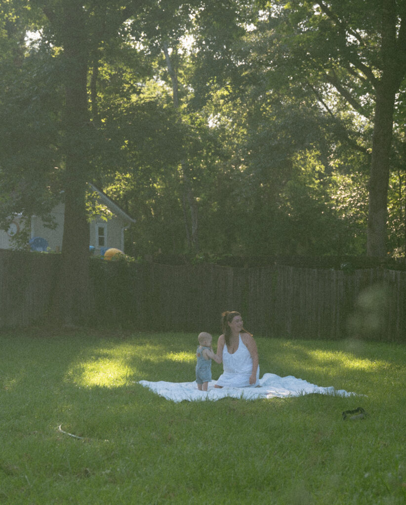 mom and baby playing on picnic blanket in backyard