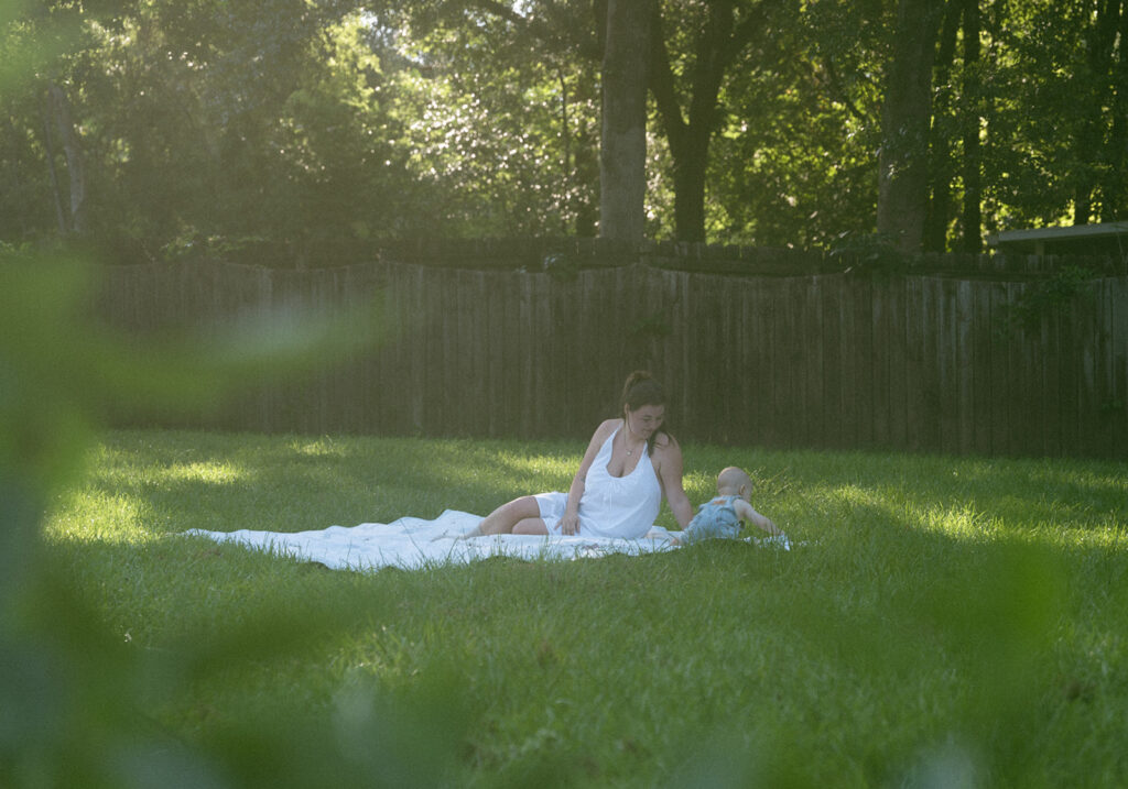 mom and baby playing on picnic blanket in backyard