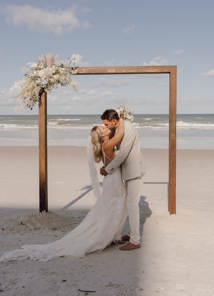 bride and groom kissing on the beach during ceremony