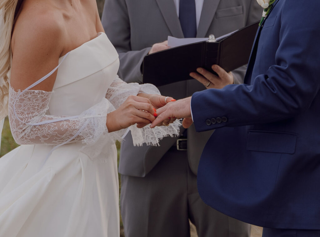 bride putting ring on groom's finger during ceremony