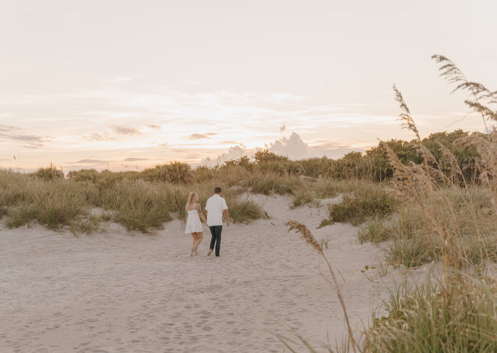couple holding hands and walking in the sand