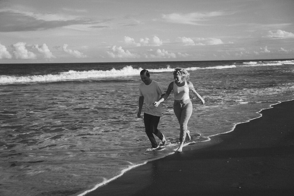 couple holding hands and running on the beach