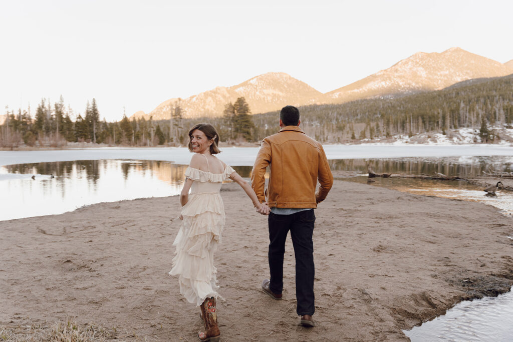 bride and groom running towards the mountains holding hands