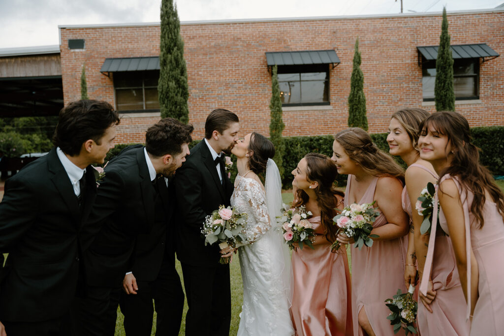 candid bridal party photos with bride and groom kissing
