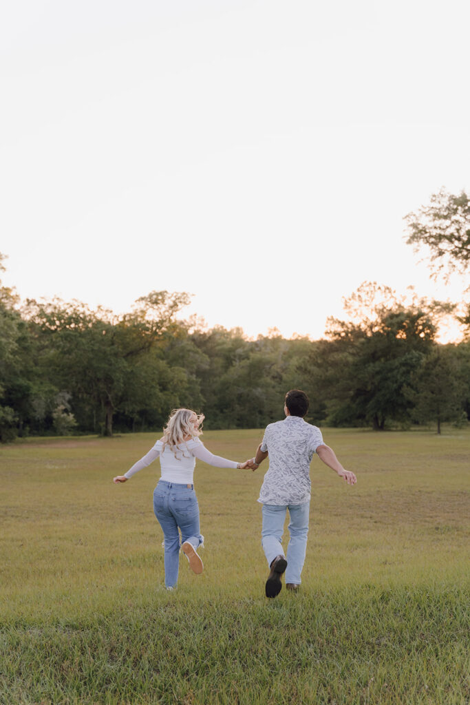 couple holding hands and running in a field