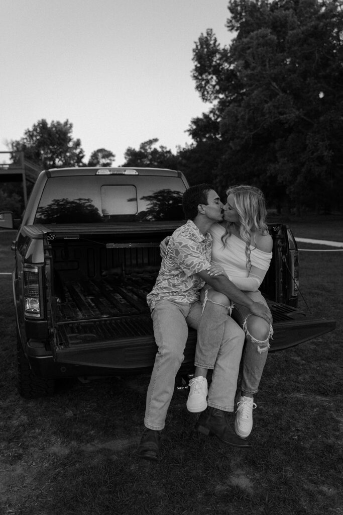couple kissing sitting on the truck bed