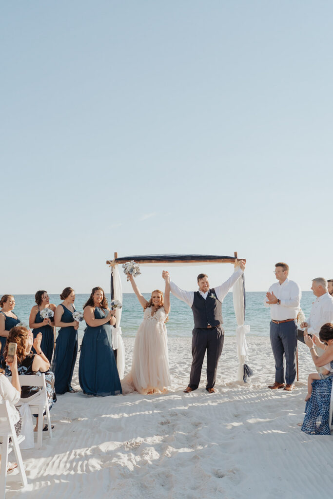 Bride and groom with their hands in the air while guests cheer.