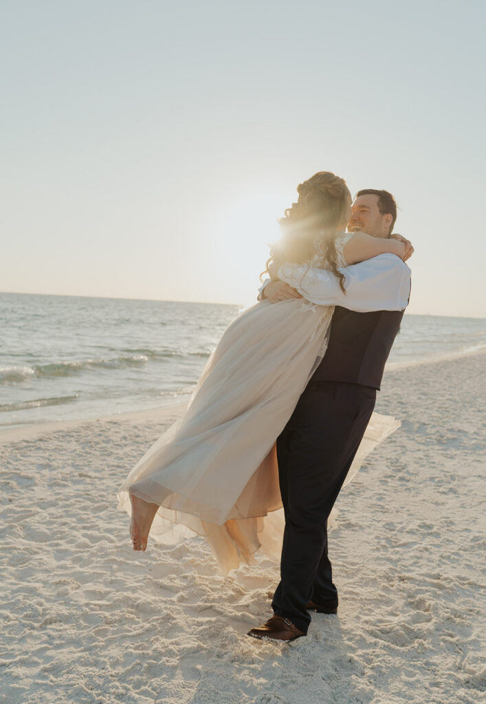 Groom romantically spinning his wife in the air during their 30A beach wedding.