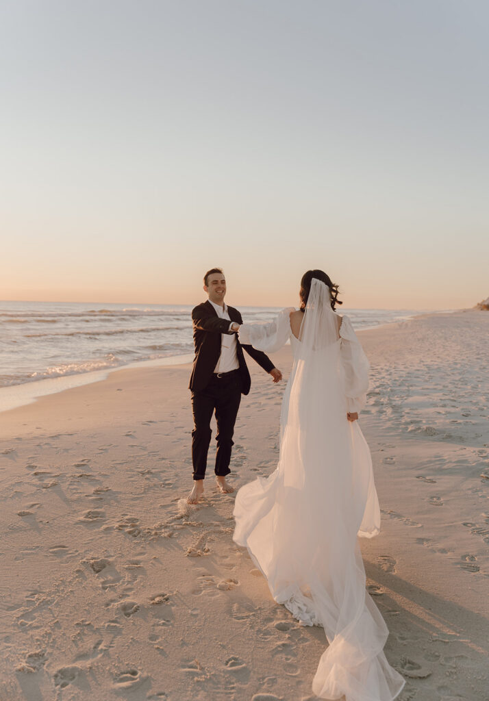 A bride and groom holding hands on the beach after their 30A beach wedding.