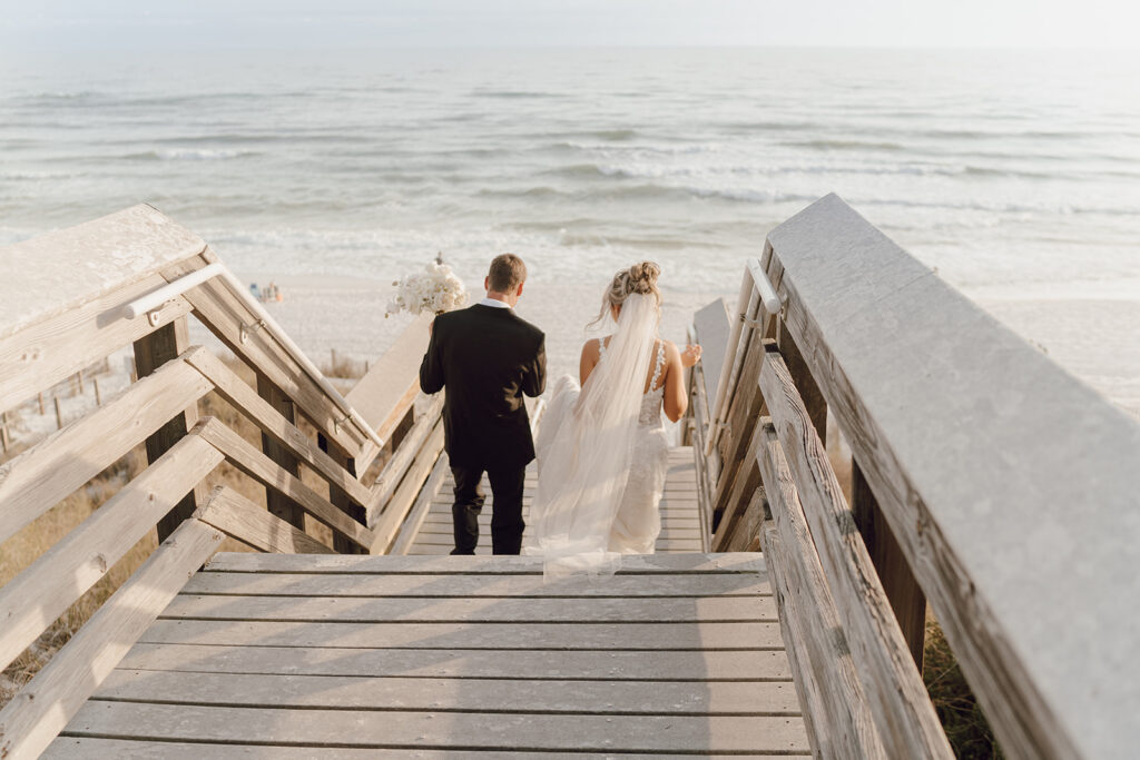 Newlyweds walking down the boardwalk to the ocean.