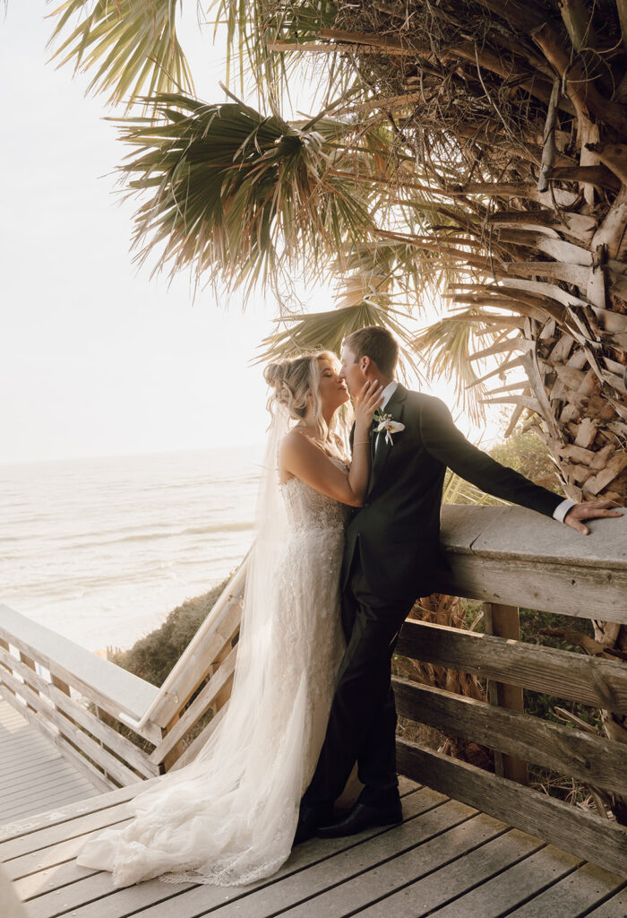 Newlyweds about to kiss under a palm tree at the beach in 30A.